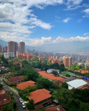 View of high rise residential brick buildings of El Tesoro neighborhood in Medellin, Colombia. Clouds breaking to reveal blue sky.