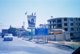 Welcome to/Bienvenue Chtaura, Lebanon. A Hezbollah sign erected after the summer war welcomes visitors to the town, behind the sign a building damaged from the most recent war. Much of the city is being rebuilt.